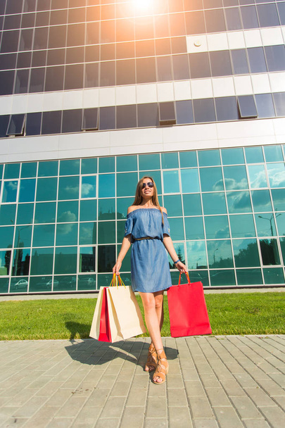 Compra, descuento y concepto de personas - retrato de mujer joven en vestido caminando con bolsas de compras de colores
 - Foto, Imagen
