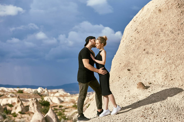 In love Eastern couple in mountains of Cappadocia hugs and kisses. Love and emotions loving couple vacationing in Turkey. Closeup portrait man and woman. Beautiful Crescent moon earrings on girl ears - Photo, Image