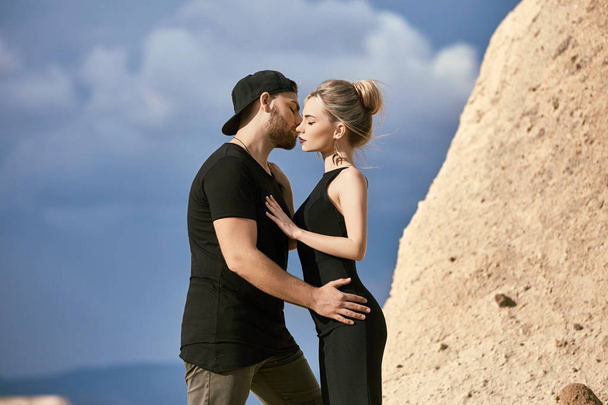 In love Eastern couple in mountains of Cappadocia hugs and kisses. Love and emotions loving couple vacationing in Turkey. Closeup portrait man and woman. Beautiful Crescent moon earrings on girl ears - Φωτογραφία, εικόνα