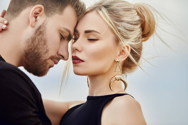 In love Eastern couple in mountains of Cappadocia hugs and kisses. Love and emotions loving couple vacationing in Turkey. Closeup portrait man and woman. Beautiful Crescent moon earrings on girl ears - Zdjęcie, obraz