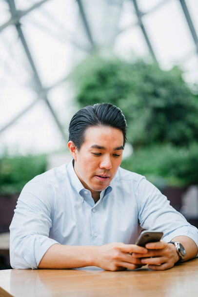 Asijský podnikatel pomocí mobilního telefonu v kanceláři - Fotografie, Obrázek
