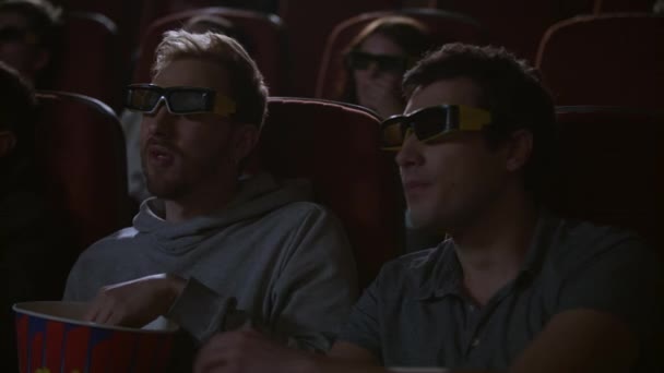 Man eating popcorn in 3d cinema. Spectactors enjoy cinema snacks - Footage, Video
