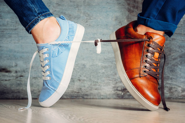 Miesten ja naisten kengät menevät eri suuntiin ja sidottu nauhoilla. Käsitys ongelma pari suhde
 - Valokuva, kuva