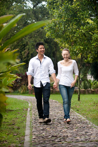 Ασιατικές ζευγάρι, κρατώντας τα χέρια να βαδίζετε στο δρόμο πάρκο - Φωτογραφία, εικόνα