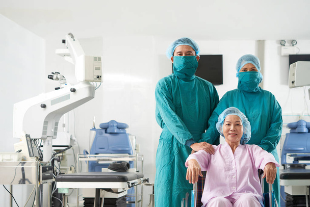 Professionele artsen met lachende Aziatische vrouw in patiënt stoel  - Foto, afbeelding
