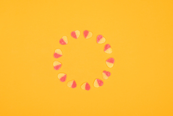 turuncu üzerinde izole kalp şeklinde Jöleli şekerler çemberi üstten görünüm - Fotoğraf, Görsel
