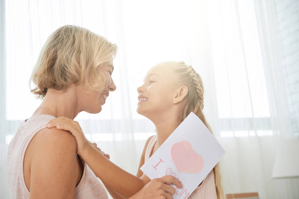 Happy hugging mother and daughter in sunny room - Photo, image
