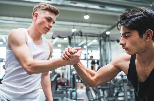 A friendly handshake of two young men in crossfit gym. - Фото, зображення