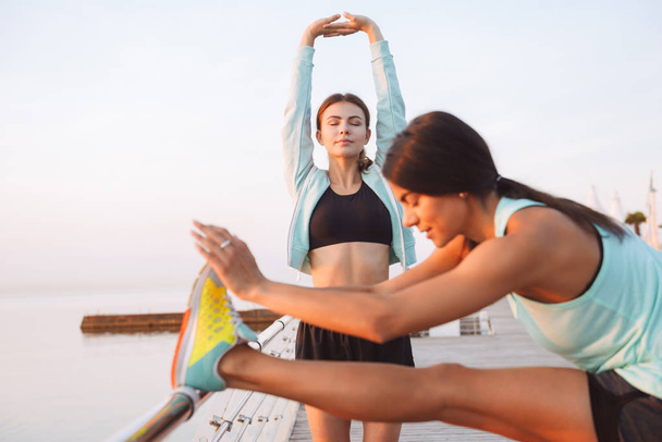 Obrazu, niesamowity młody dwa sportu kobiet przyjaciół na zewnątrz na plaży zrobić ćwiczenia sportowe. - Zdjęcie, obraz
