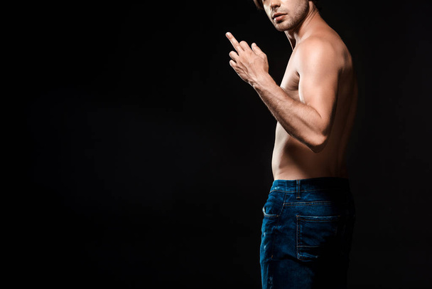 partial view of shirtless man showing middle finger to camera isolated on black - Zdjęcie, obraz