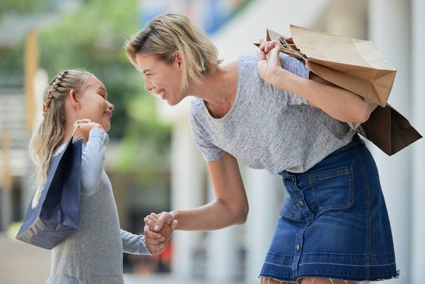 Happy woman with shopping bags holding hand of daughter - Photo, Image