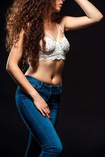 partial view of woman in white bra and jeans posing isolated  on black - Φωτογραφία, εικόνα