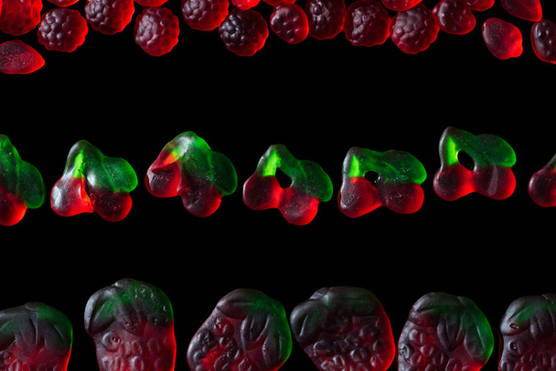 top view of jelly candies in shape of raspberries, strawberries and cherries isolated on black - Foto, immagini