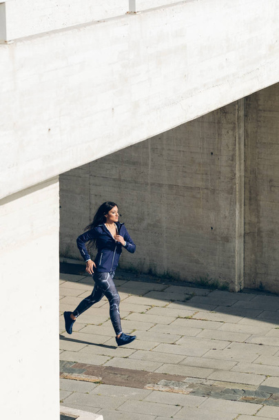 Female urban athlete running in the city. Healthy lifestyle and exercising. - Fotoğraf, Görsel