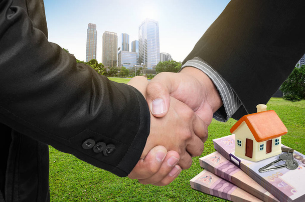 Handshake  with real estate agents, house models on banknotes and keys. The concept of home trading agreement. - Photo, Image