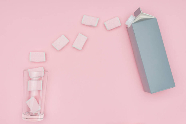 Top uitzicht op lekker marshmallows, glas en karton pakket geïsoleerd op roze  - Foto, afbeelding