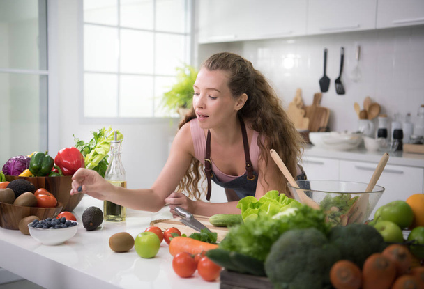 Mujer joven y saludable en una cocina preparando verduras para una comida saludable y ensalada
 - Foto, imagen