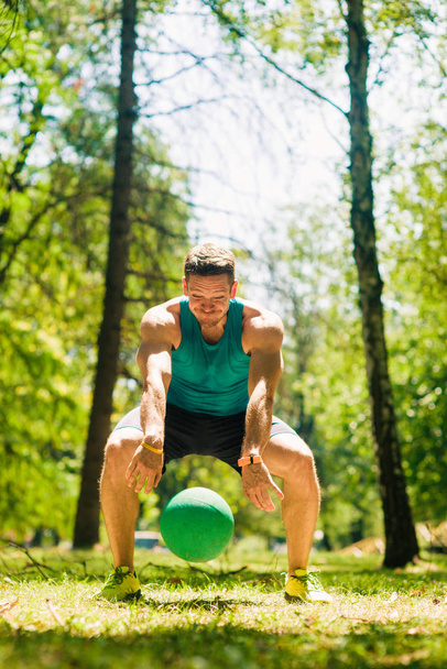 Sportive τύπος διασκεδάζοντας με ιατρική μπάλα στο χόρτο - Φωτογραφία, εικόνα
