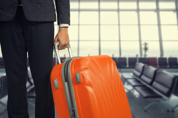 Homme d'affaires et valise dans le salon de départ de l'aéroport, avion en arrière-plan flou, concept de vacances d'été, valises de voyageur dans la zone d'attente du terminal de l'aéroport
. . - Photo, image