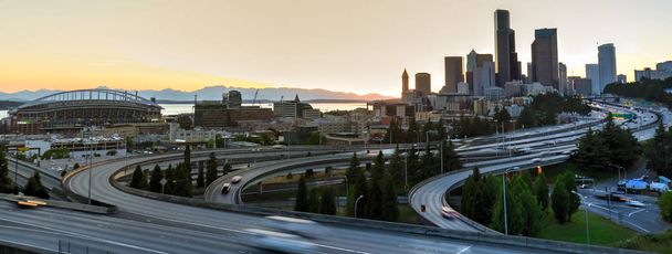 Panoramic view Seattle skylines and s-curved I-90, I-5 highway interchange traffic motion during sunset. Travel and transportation background, cityscape and high speed concept. View from Rizal Park - Photo, Image