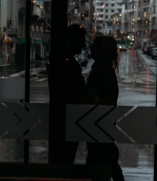 silhouette of a hugging couple against the backdrop of the city,behind a glass - 写真・画像