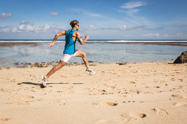 athletic man running and jumping on sand beach near sea, Bali, Indonesia - Photo, Image