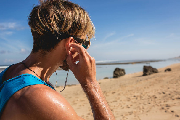 athletic man listening music with earphones on beach - Фото, изображение