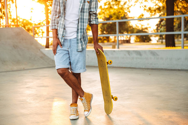 Cropped image of young african man with skateboard standing at the skate park - Foto, Bild
