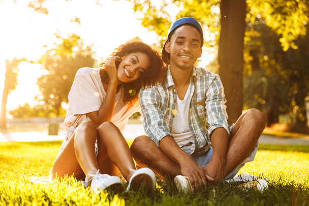 Image of cute cheerful young african loving couple sitting outdoors in park. - Valokuva, kuva