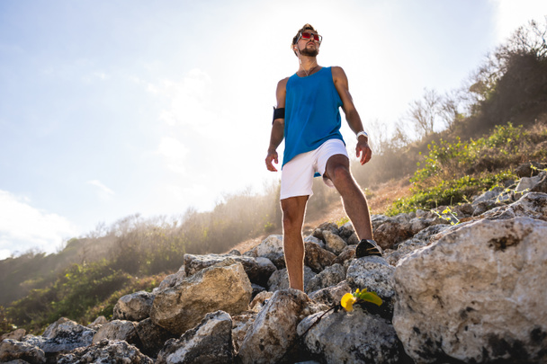 vue du bas de l'homme athlétique debout sur des rochers avec lumière du soleil
 - Photo, image