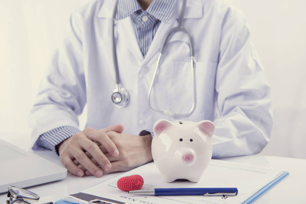 Arzt und Sparschwein auf dem Tisch Arzthonorar für die Gesundheitsversorgung. Finanzierungs- und Versicherungskonzept. - Foto, Bild