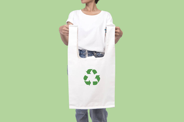 Дівчина тримає тканину на полотні з символом переробки ізольовано на зеленому тлі. еко і зберегти концепцію землі
. - Фото, зображення