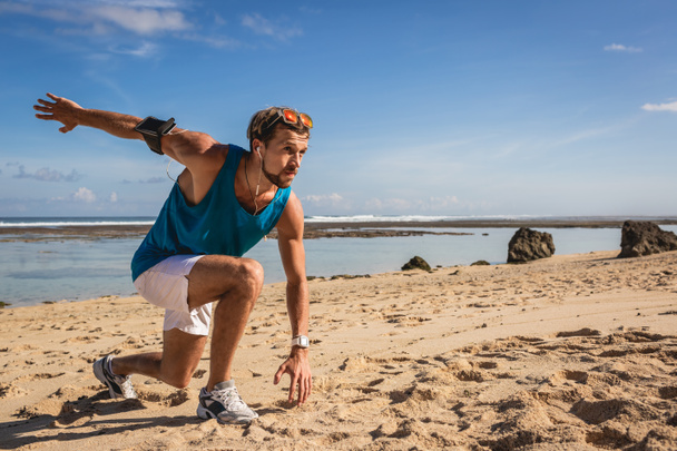 athletischer Mann mit Armbinde beim Ausfalltraining an der Küste - Foto, Bild