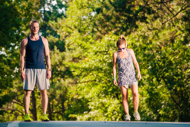 Молодая пара в хорошей форме посреди дороги делает упражнения
 - Фото, изображение