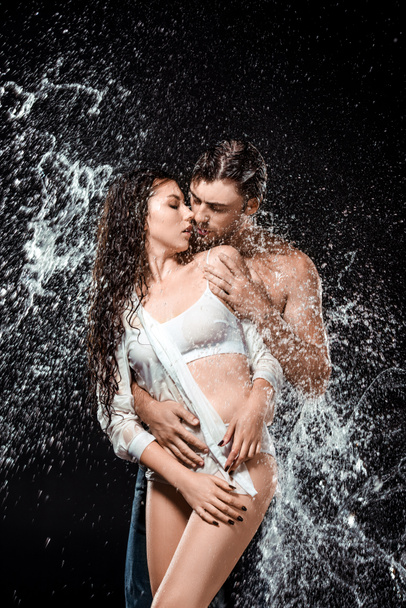 portrait of sexy young couple with water splash isolated on black - Photo, Image