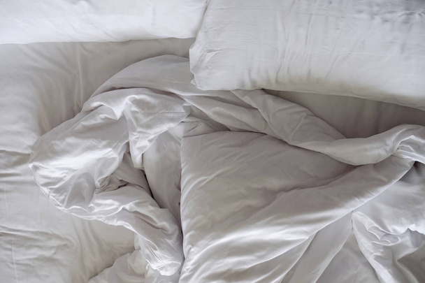 Cama desordenada. Almohada blanca y manta en el dormitorio, relajación y concepto cómodo
  - Foto, imagen