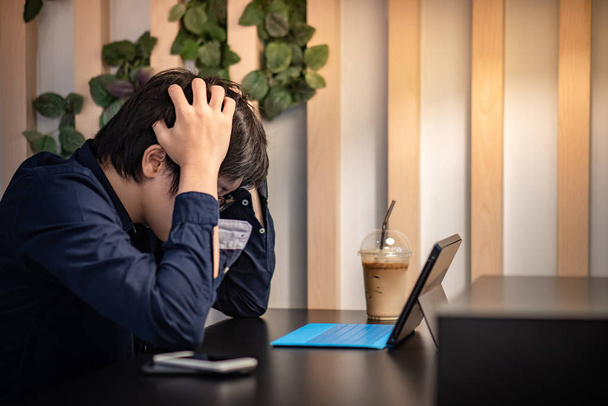 Joven empresario asiático sentirse estresado y frustrado mientras trabaja con la tableta digital en la cafetería. Concepto de problema empresarial
 - Foto, Imagen