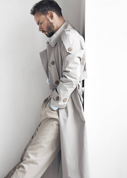 Fashion portrait of man with dark beard and hair, weared in light trench coat and beige pants.  - Фото, зображення