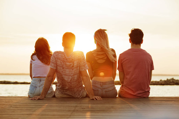 Back view photo of group of four friends loving couples walking outdoors on the beach. - Photo, image