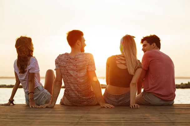 Back view photo of group of four friends loving couples walking outdoors on the beach. - 写真・画像