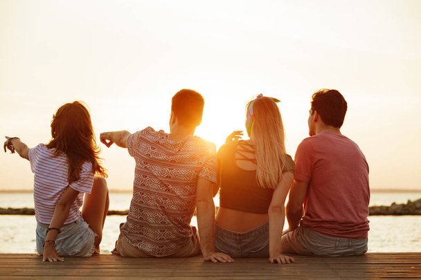 Back view photo of group of four friends loving couples walking outdoors on the beach. - Foto, Imagen