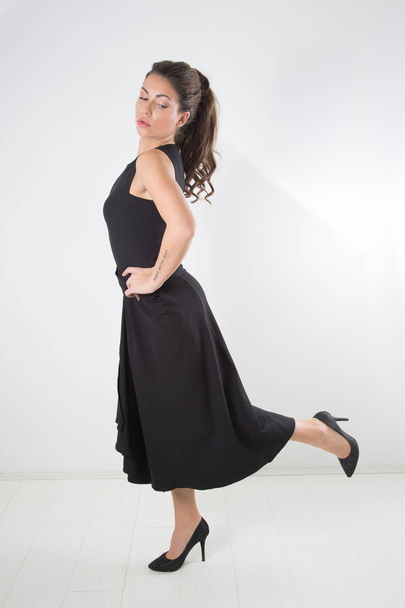 Side View Of Woman Posing In Black Elegant Dress And Looking Down, Full-Length Studio Shot Over White Background - Foto, afbeelding