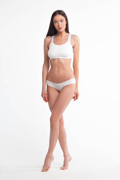 Slim young woman in underwear on white background. Skin and body care concept - 写真・画像