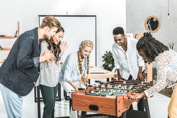 multicultural businessmen and businesswomen playing table football together in office - Foto, Bild