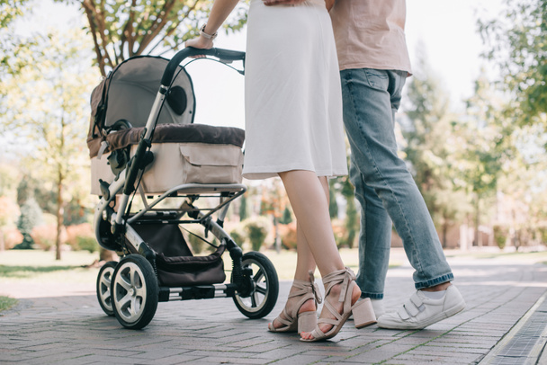 cropped image of parents walking with baby carriage in park - Foto, afbeelding