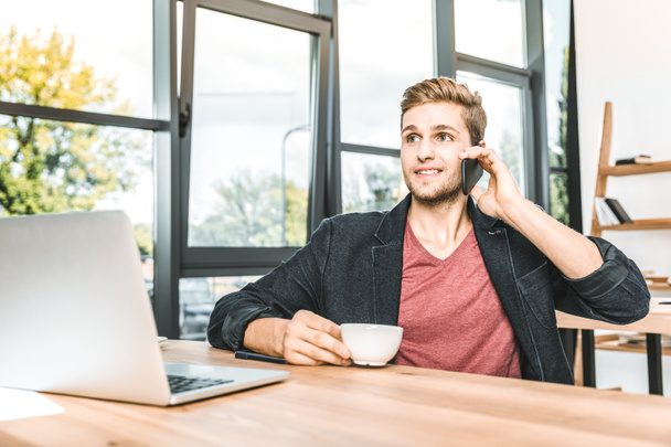 retrato del joven hombre de negocios hablando en el teléfono inteligente en el lugar de trabajo en la oficina
 - Foto, imagen