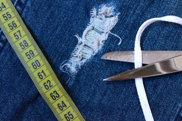 Измерение ленты на синих джинсах, шитье одежды
 - Фото, изображение