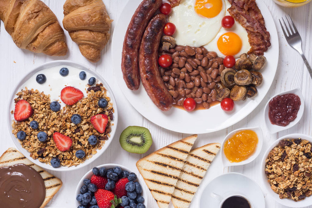 Здоровый сбалансированный английский завтрак с йогуртом, ягодами, фруктами, кофе и соком
 - Фото, изображение