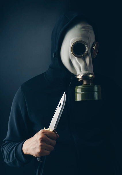 Zločince ohrožující koncept, strašidelné zloděj v plynové masce s bojový nůž hledá oběť - Fotografie, Obrázek