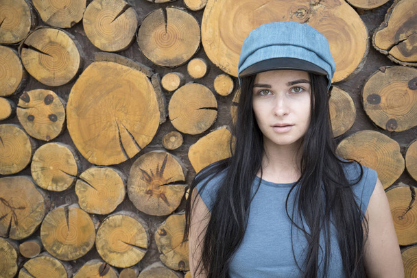 Portrait of a girl on a wooden background. Girl with a blue hat. Portrait of a girl in a cap. Beautiful brunette - Foto, afbeelding